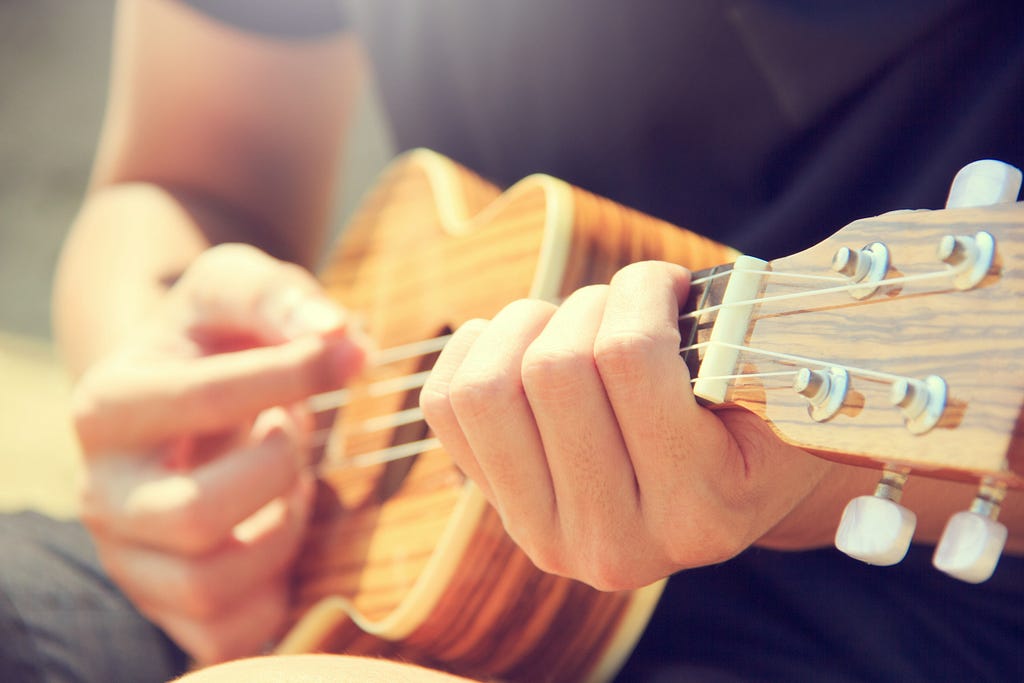 Hands playing a wooden ukulele. — Photo by Porapak Apichodilok from Pexels