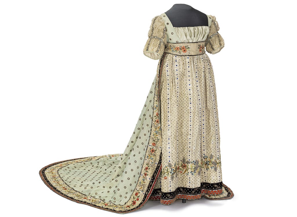 A womens tailing dress with green floral pattern on white/yellow fabric.