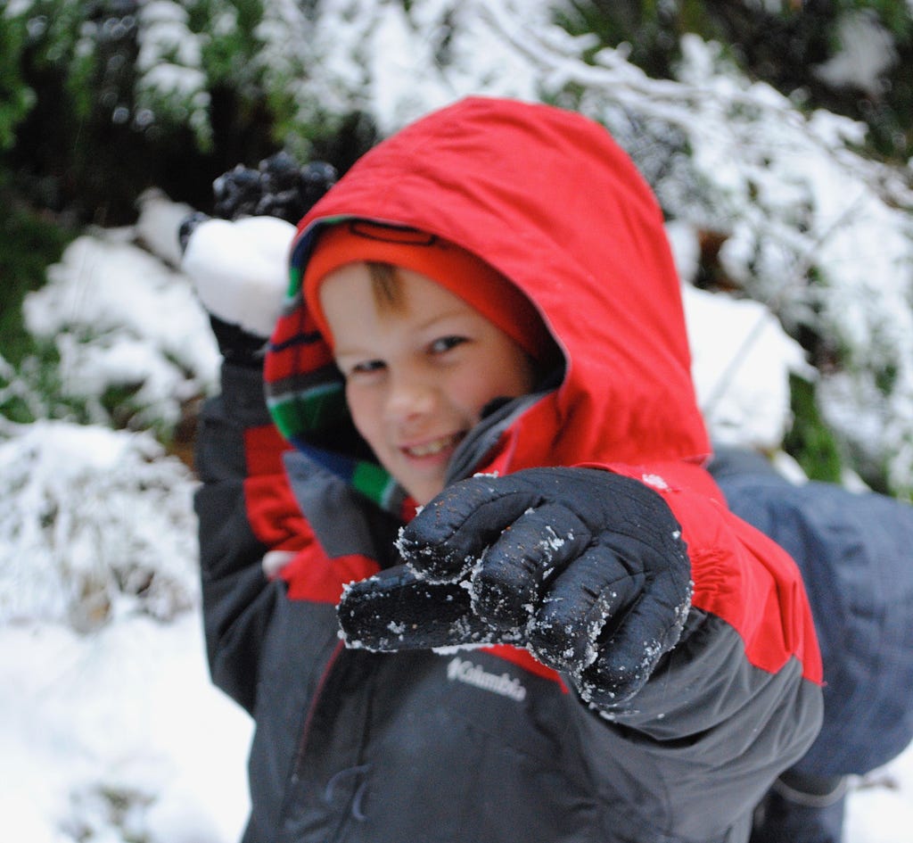 A boy about to throw a snowfall at your face for fooling around.