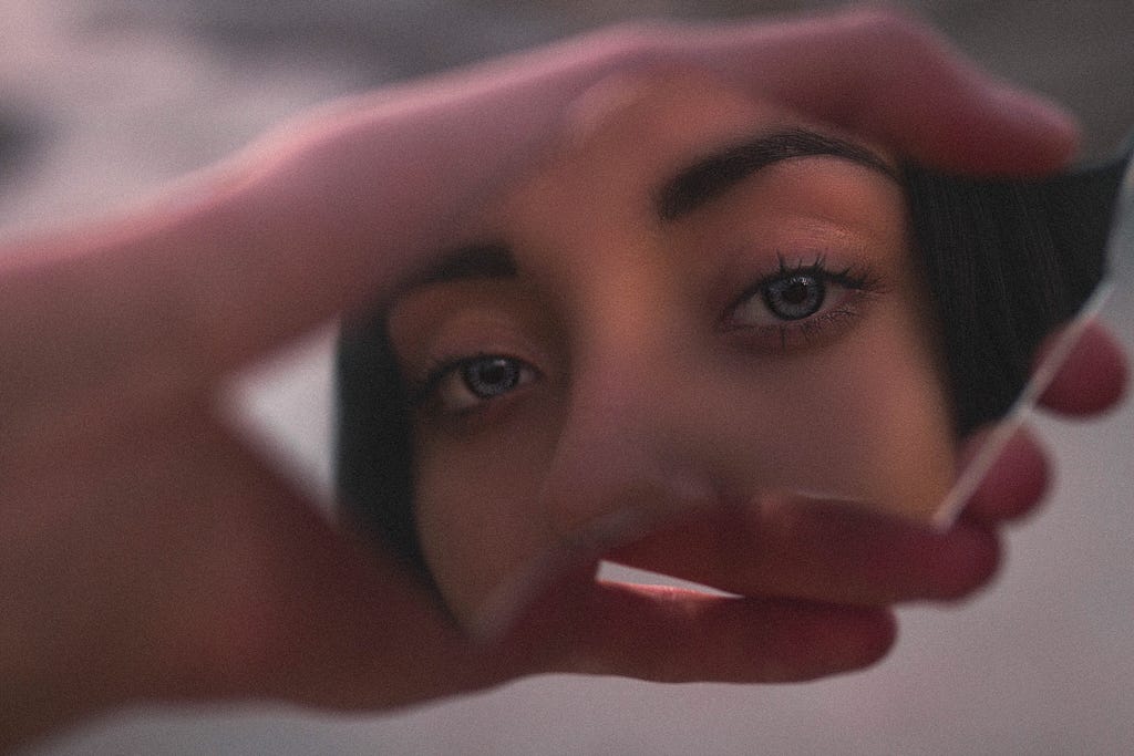 Focus on woman’s blue eyes in broken mirror shard