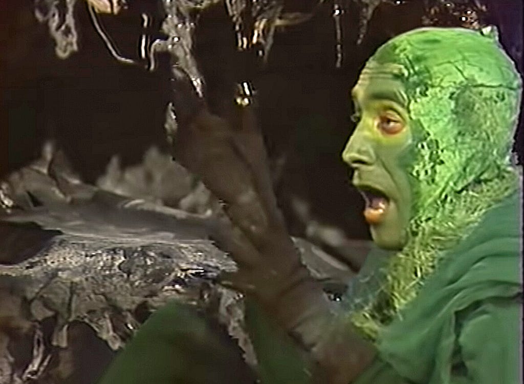 A still from the Soviet adaptation of Lord of the Rings. Gollum in his cave, with webbed fingers and a green, cabbage-like head.