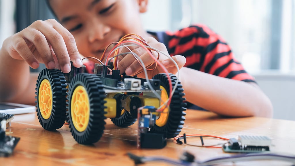 Concentrated boy creating robot at lab