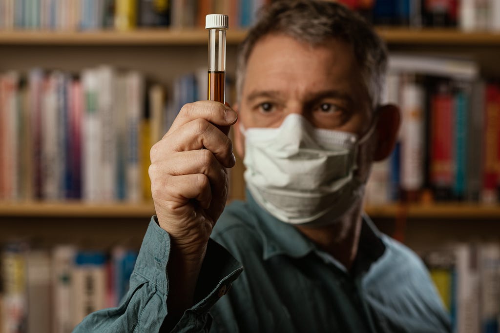 Man wearing mask looking at vile.