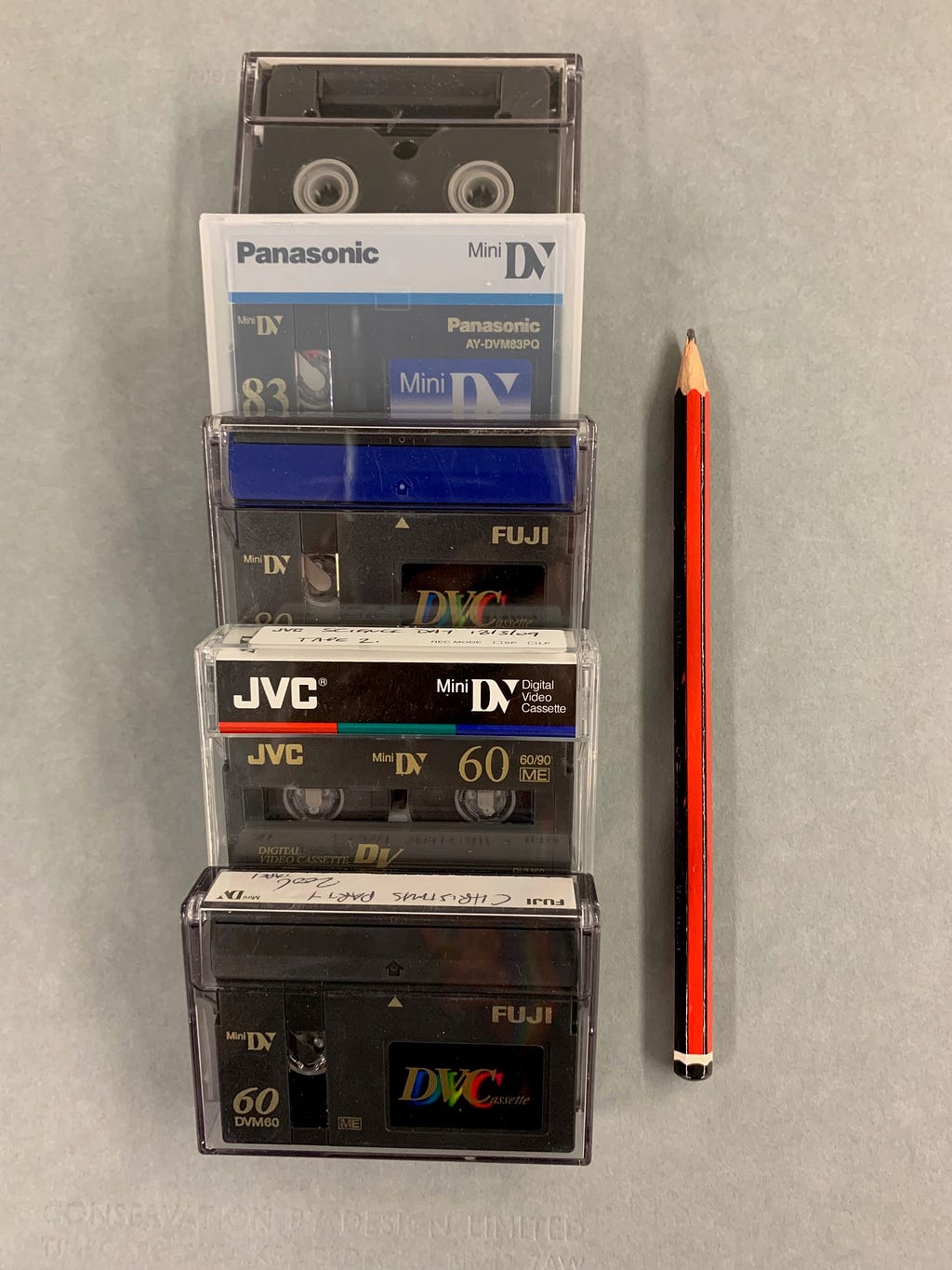 set of mini digital video tapes next to a pencil demonstrating their small size
