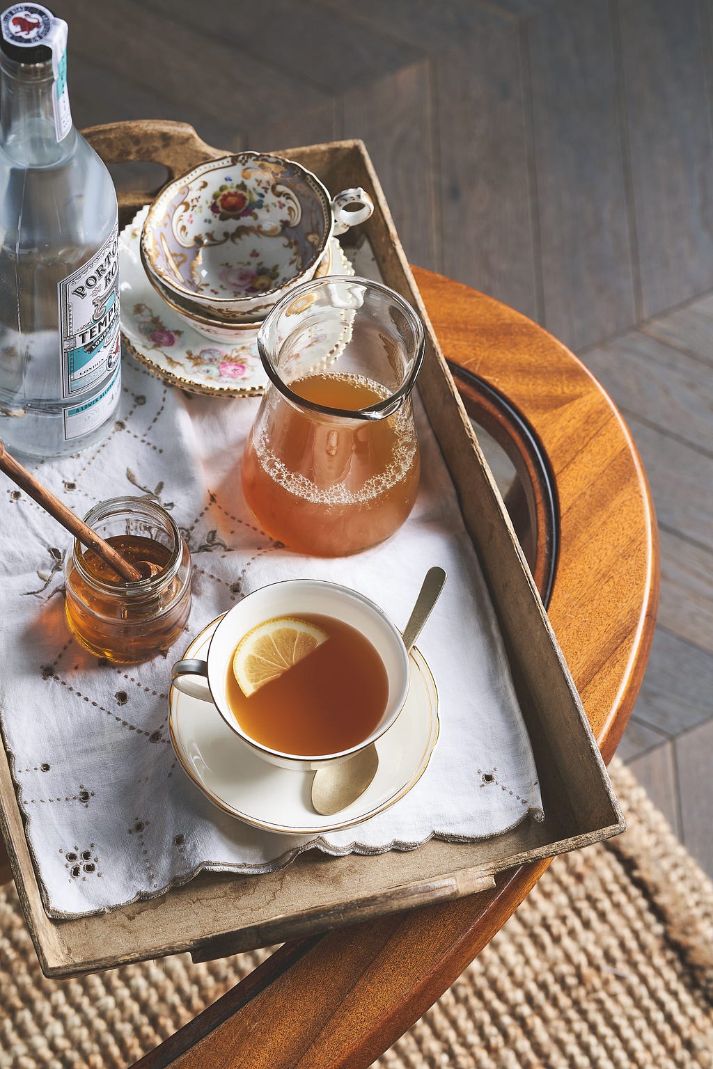 a tea tray with a teacup with a drink inside and a pot of honey on the tray
