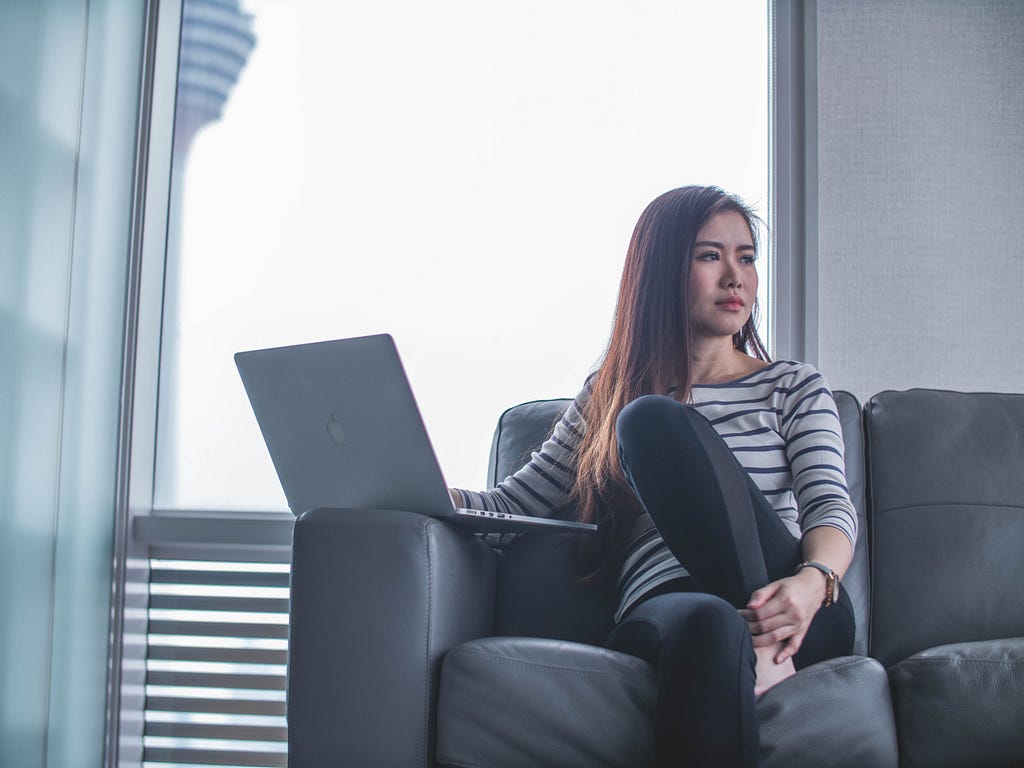 a young person sitting on a couch with their laptop open