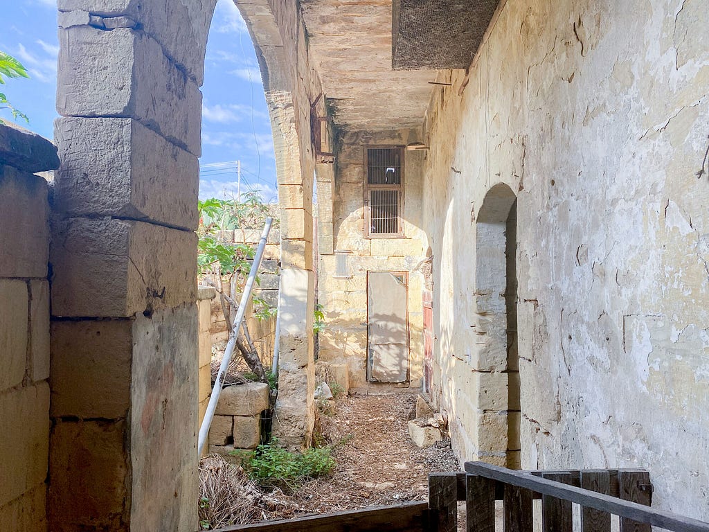 A view of the outside of the property with high arches and a bit of Maltese sky.