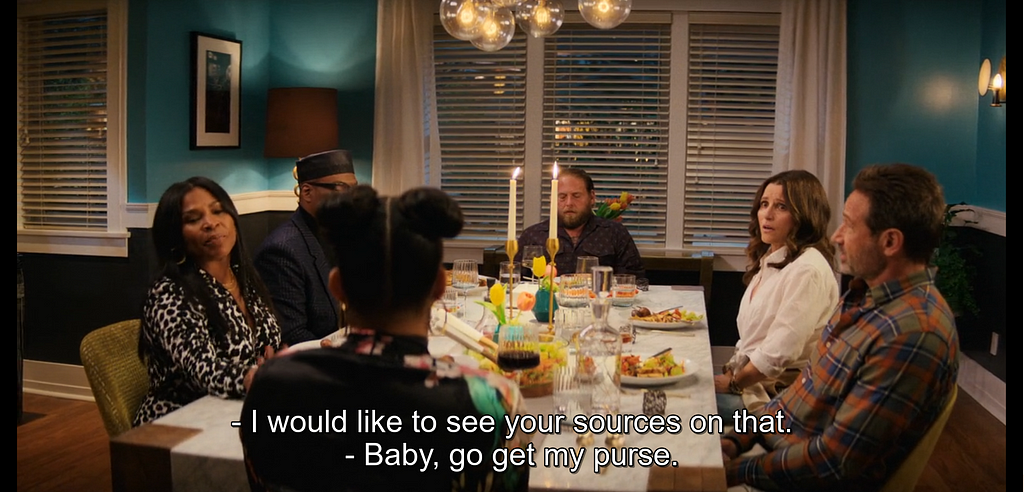 A shot of six people at a dinner table. All who’s faces are visible look agitated or otherwise upset. Subtitles read, ”I would like to see your sources on that.”… “Baby, go get my purse.”