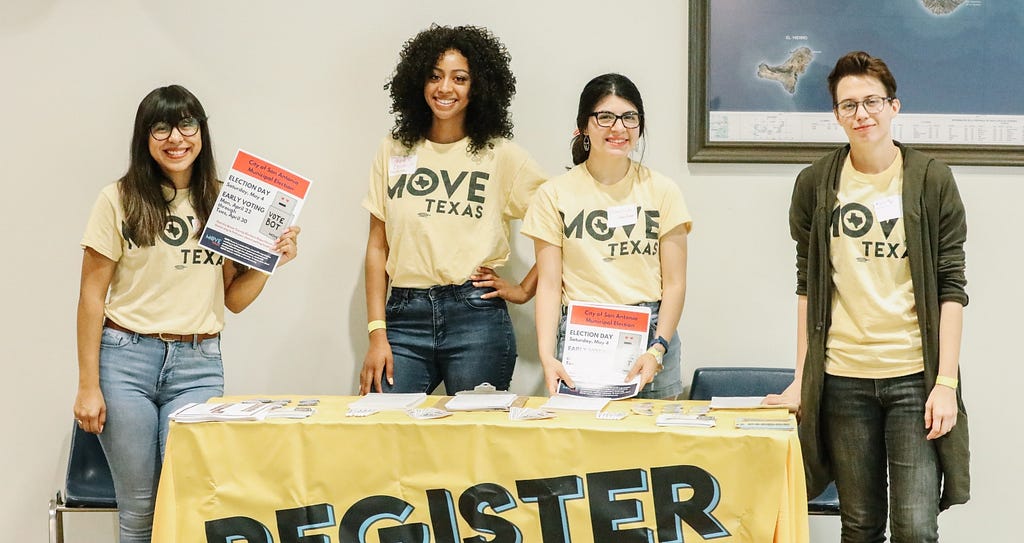 Four students work at a voter registration table