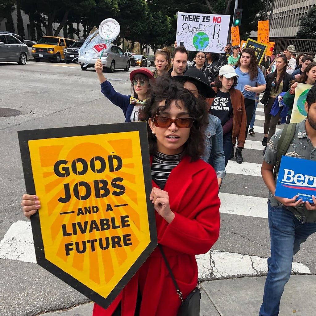 At an LA Climate Strike a marcher holds a sign that reads “Good Jobs And A Livable Future”