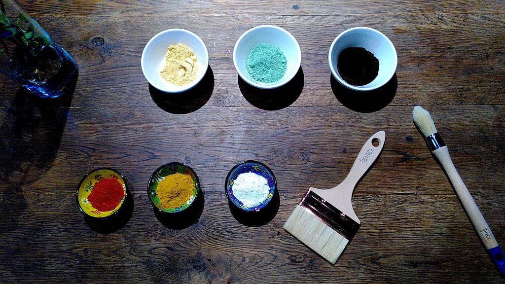 Samples of natural earth based pigments and brushes on a wood table