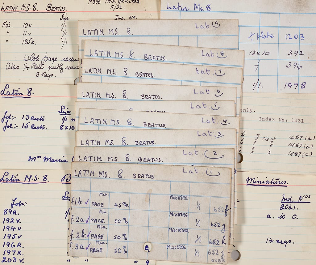 A variety of index cards relating to Latin MS 8 spread out over a surface