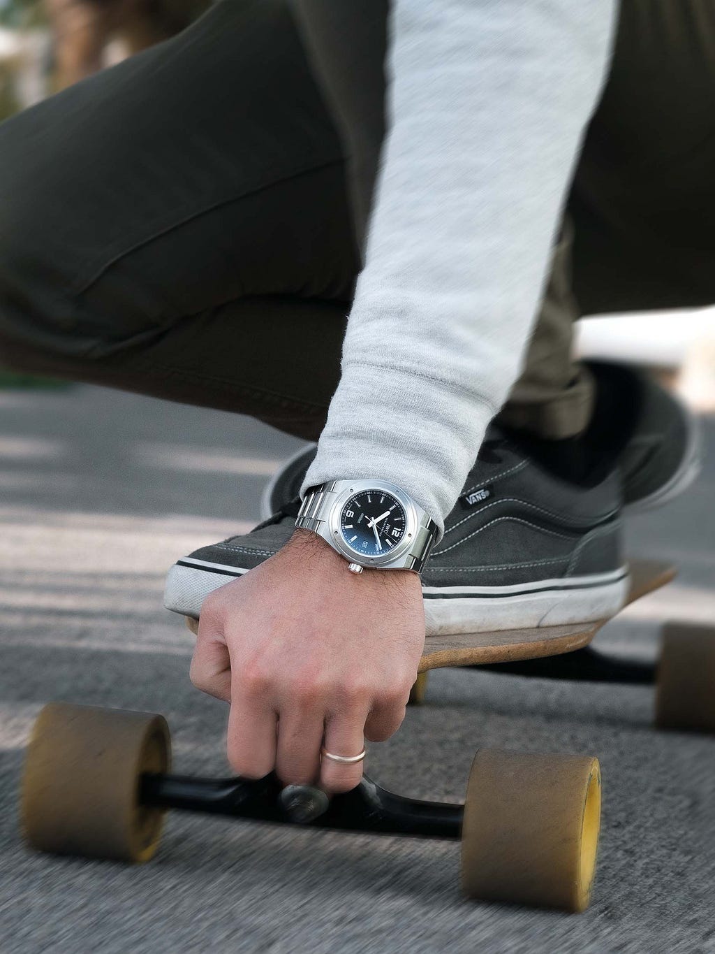 Man wearing a IWC Ingeneur wrist watch while riding is longboard. Motion blur