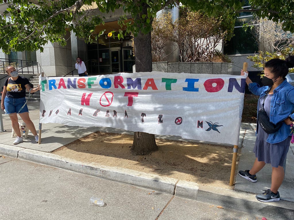 Marlene Sanchez, Deputy Director of the Ella Baker Center, and Nicole Lee, Executive Director of Urban Peace Movement, hold a sign that reads “Transformation Not Incarceration” at a protest outside the Alameda County Probation office in Oakland.