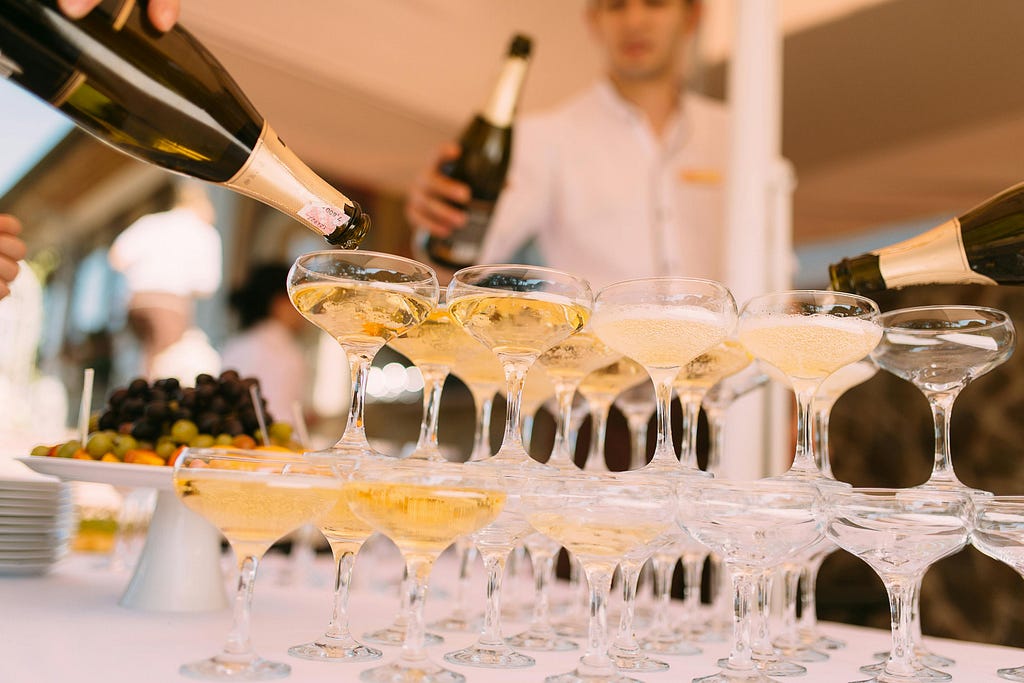 Person pouring champagne in cocktail glasses