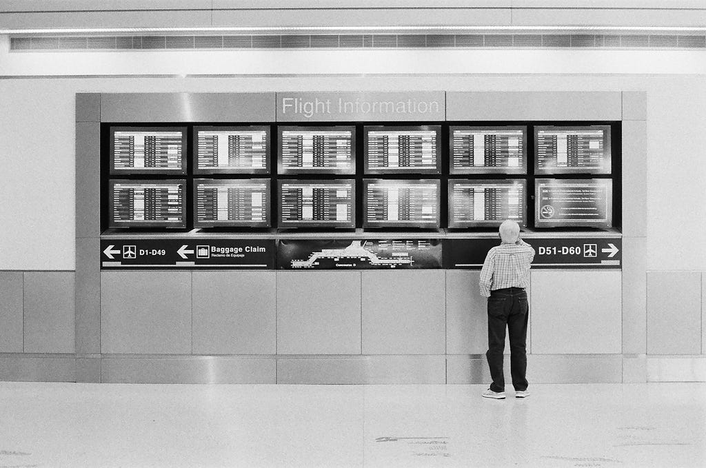 A man looking at several screens for his flight information
