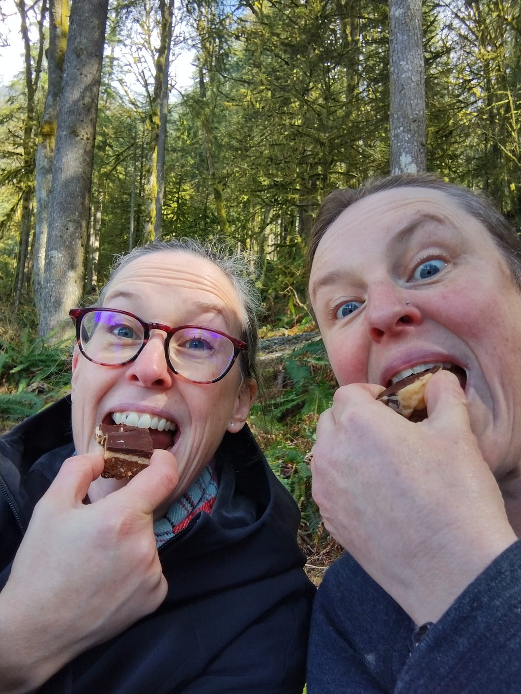 a photo of me and my sister eating Nanaimo Bars while taking a break from a hike at Buntzen Lake