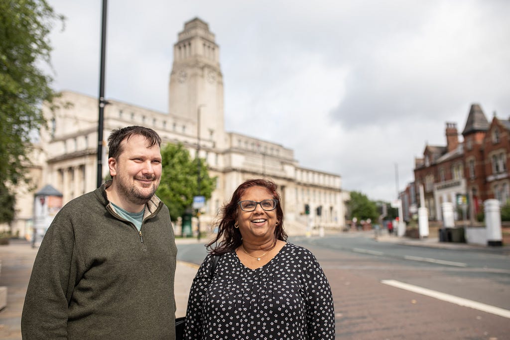 Two mature students at the University of Leeds photographed outside the Laidlaw Library with the iconic Parkinson Building in the background.