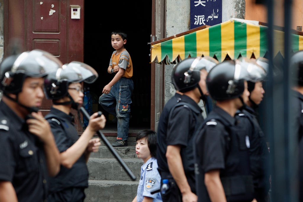 An ethnic Uyghur boy stands at the door of his home as Chinese security forces secure the area in Urumqi, China, July 10, 2009. Photo by Nir Elias/Reuters