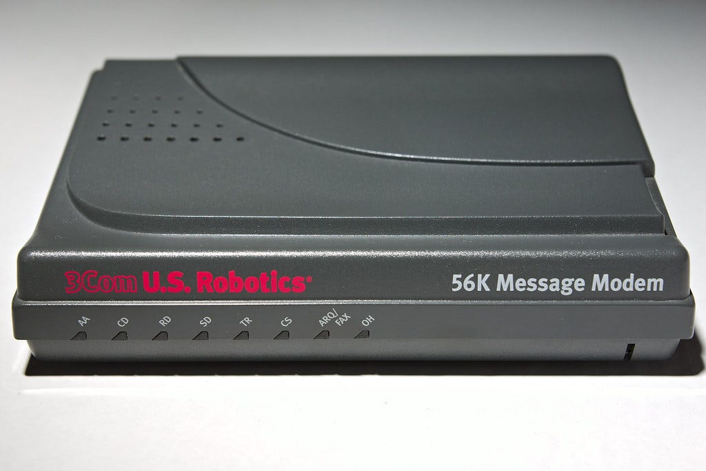 A US Robotics modem — it’s a grey, horizontal box with 8 lights on the front. It’s about 3cm high, 20cm long and 10cm deep.