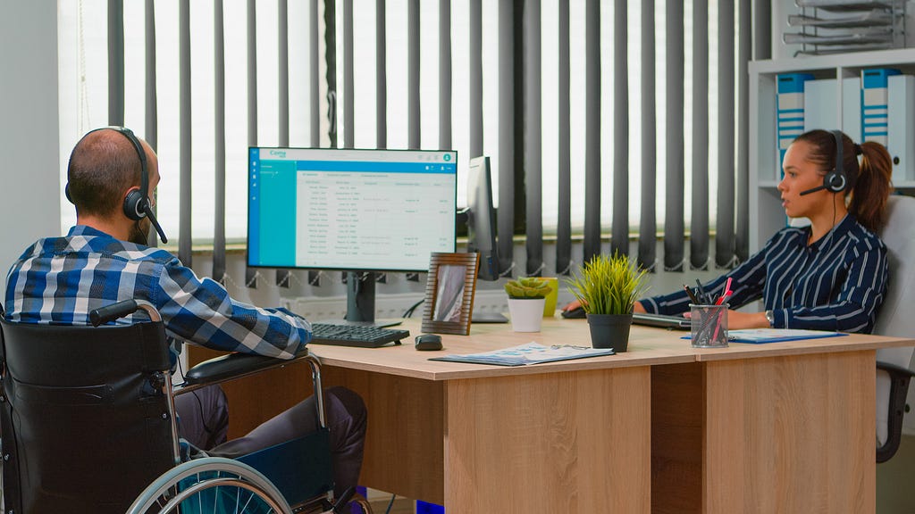 Two customer service employees working. One is on a wheelchair.