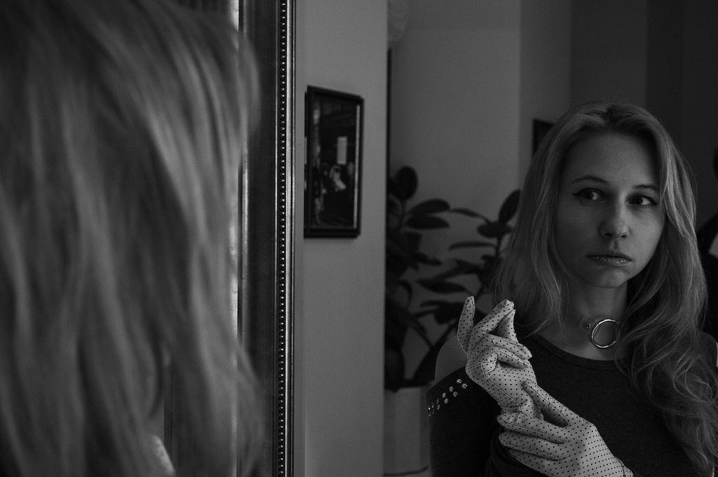 black and white image of a woman looking in a mirror