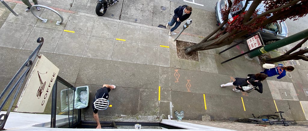 an overhead photo of the sidewalk with yellow tape lines indicating where people should stand