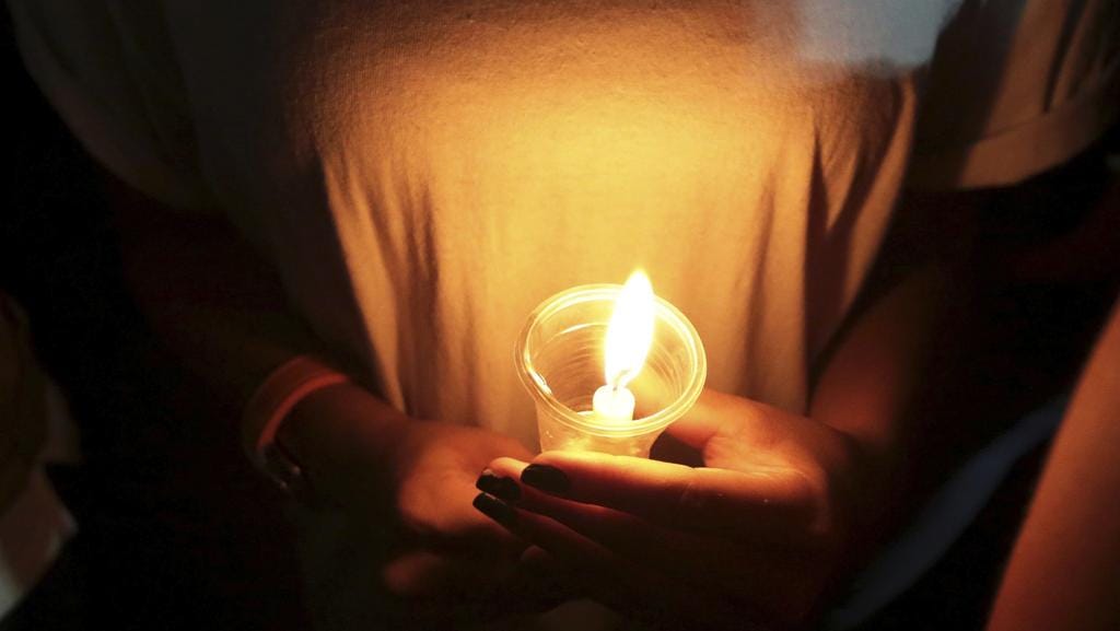 Hand holding a lit candle for a candle vigil