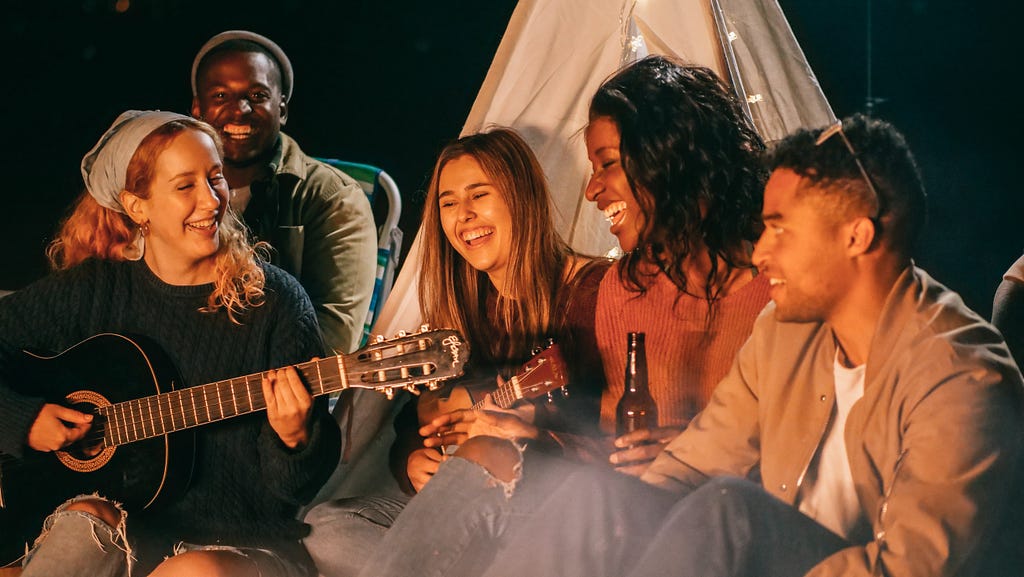 A group of friends enjoying their time playing guitar and singing depicting the noiton of traveling creating life long memories.