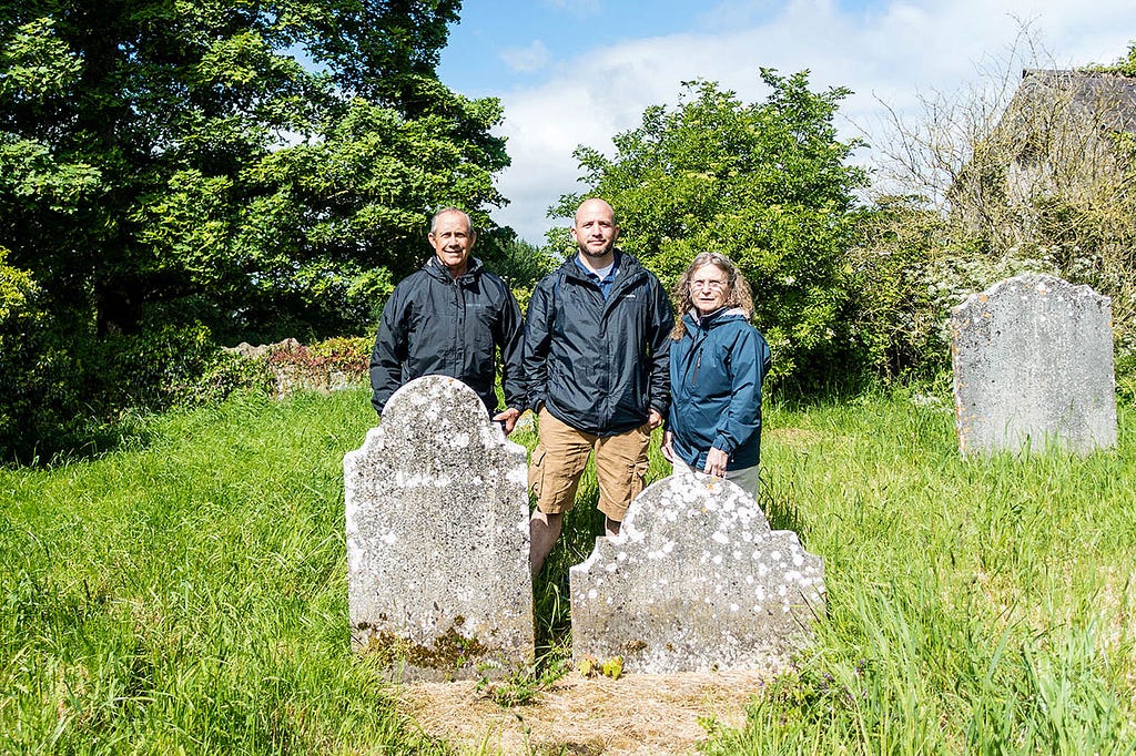 Three people standing next to two gravestone — Searching for My Relatives: Kilkenny, Ireland