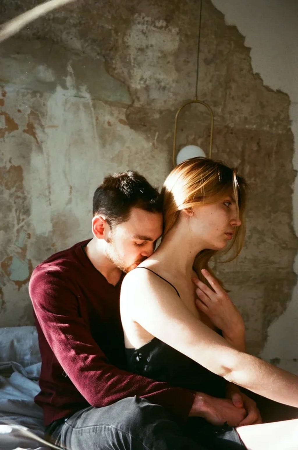 Man kissing a woman’s back when she looks lost in thoughts