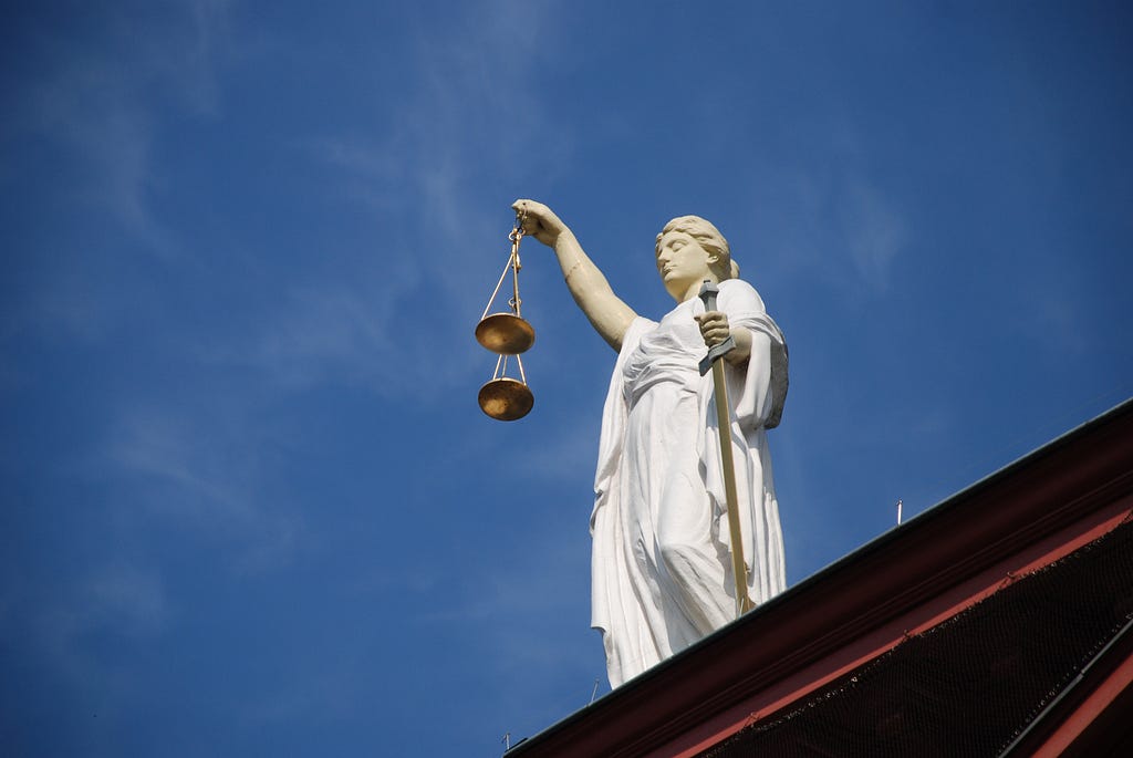 Lady Justice statue in front of a blue sky.