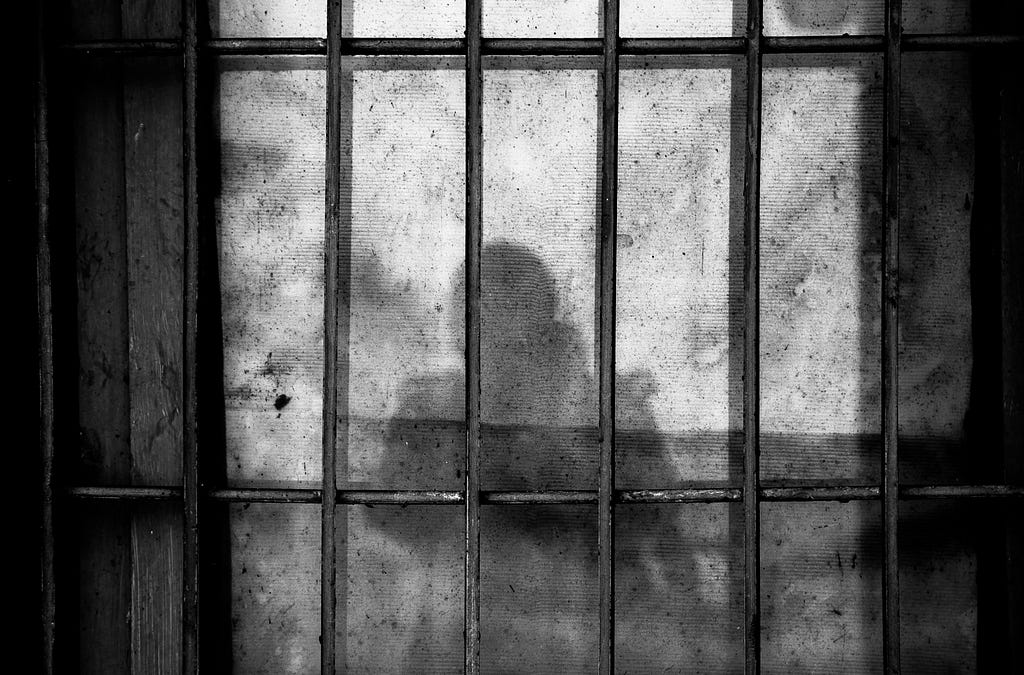 Black & White photo of an outline of a person behind bars