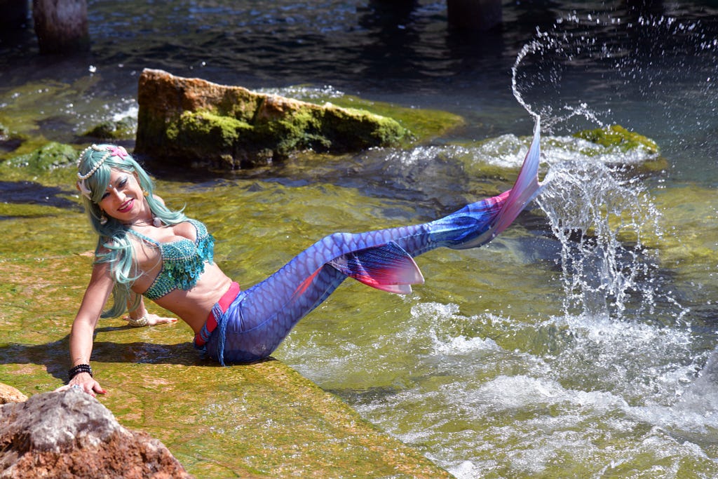 White woman dressed as a mermaid splashing in the water