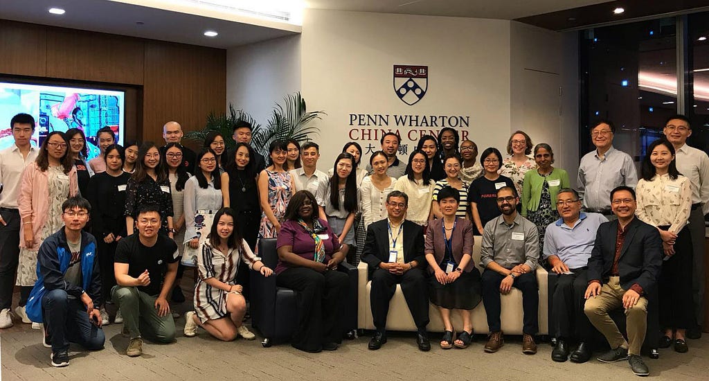 A large crowd of Forerunner 2019 participants pose in from of the Penn Wharton China Center sign.