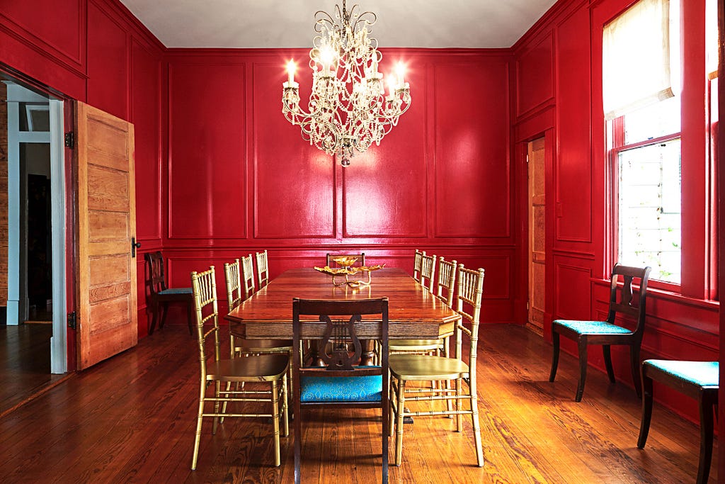 A wood-paneled dining room with a chandelier and deep red walls.
