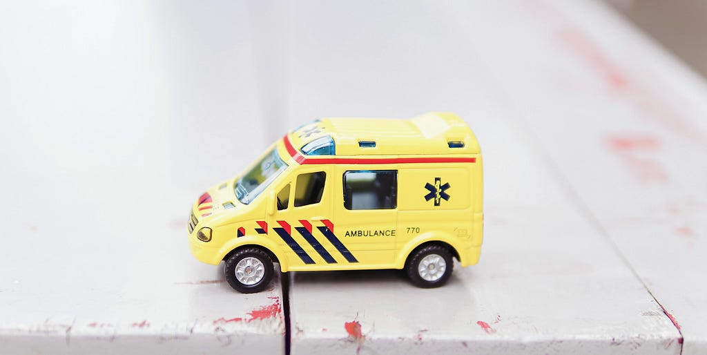 Yellow ambulance toy on white surface