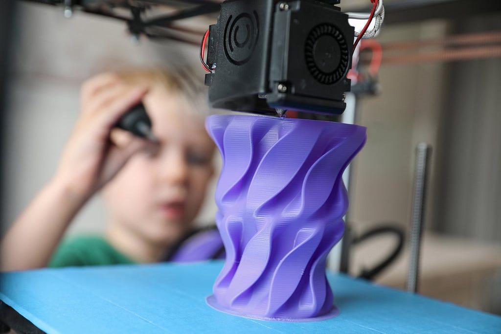 Young boy uses 3D printer to create purple mockup prototype design thanks to affordable startup cost