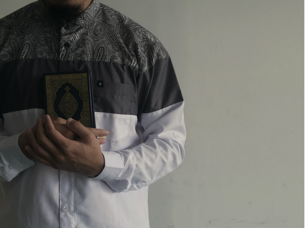 Man in white dress shirt holding Quran