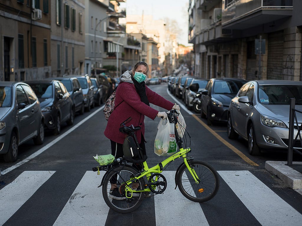 A Sparwasser volunteer, standing next to her bike on a crosswalk, delivers groceries