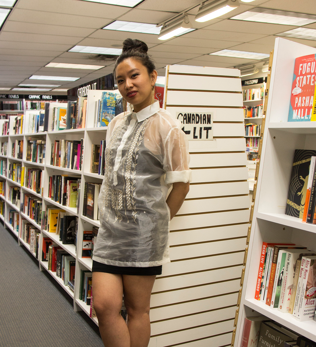 Woman standing against a bookshelf in the “Canadian lit” aisle of a bookstore