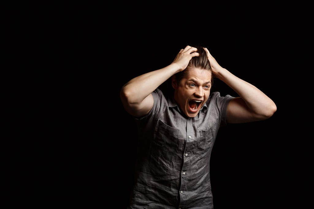 Man screaming against a black background