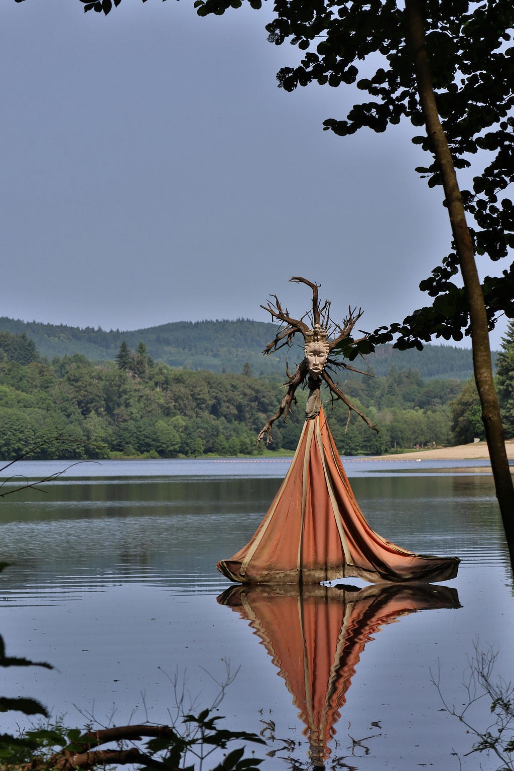 <IMG SRC=”your image.jpg” alt=”a tent on a lake surrounded by trees and a mountain at the back with a tribal wooden mask at the top”/>