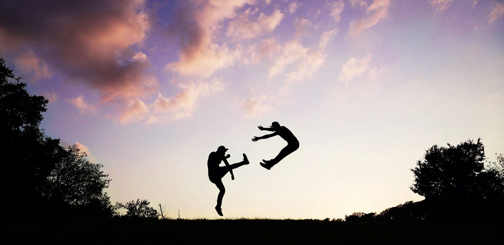 A man is sent flying through the air, presumably from a hard kick in the pants, against the backdrop of a beautiful sunrise