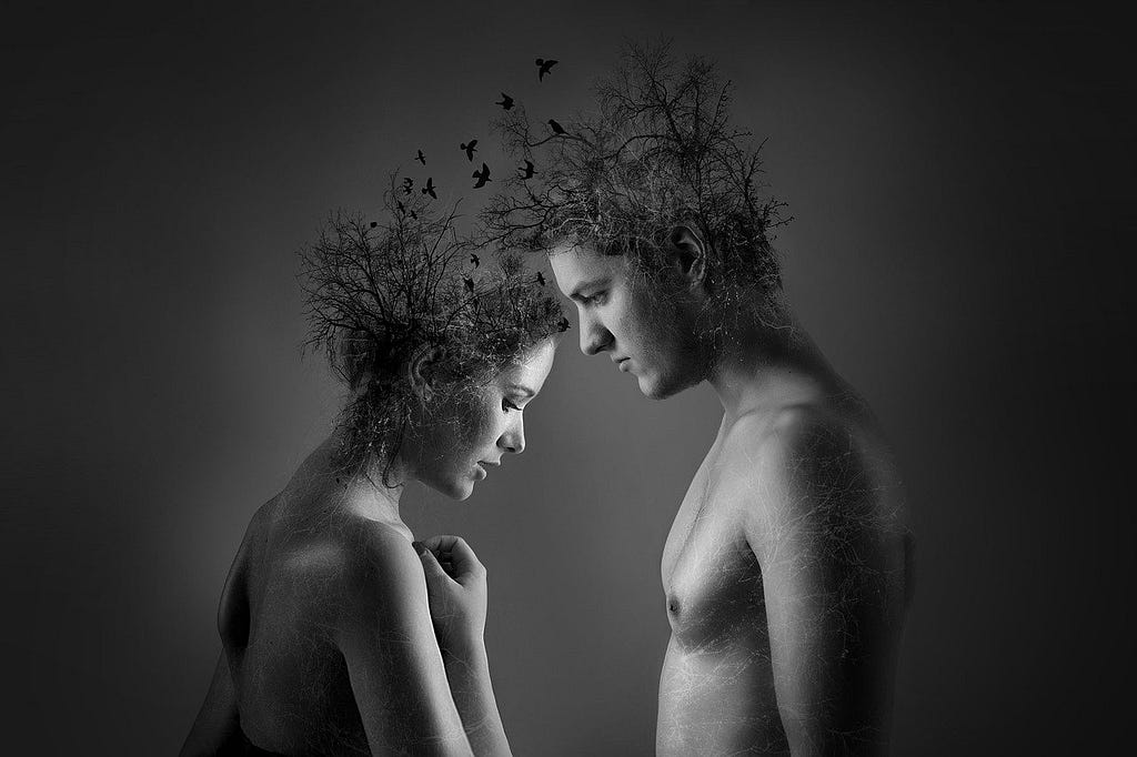 A man and a woman face each other with bowed heads, from which grow treetops and between which birds fly.