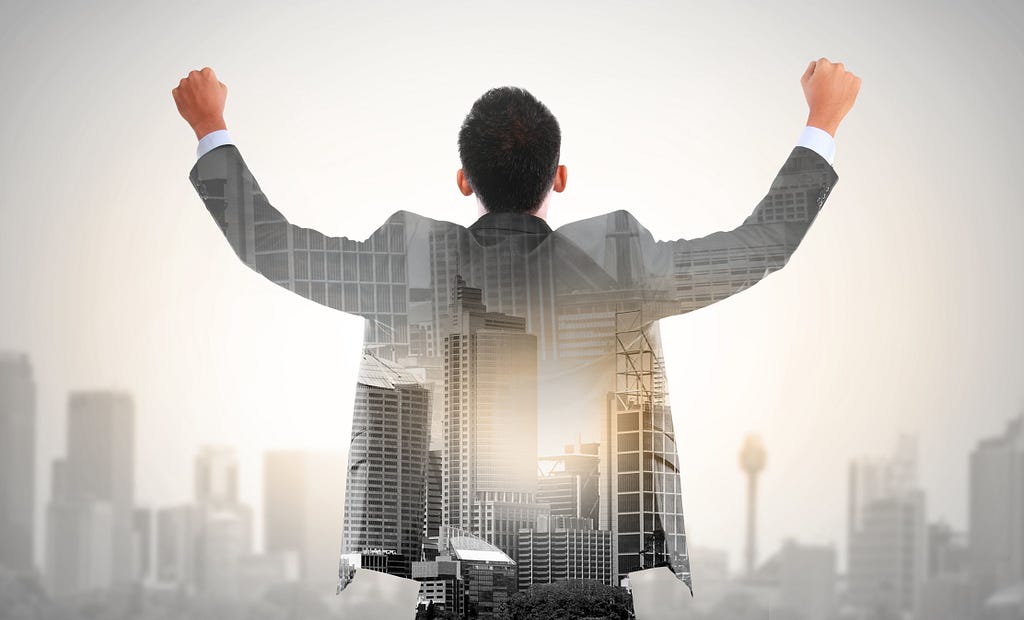 Businessman with arms raised in front of a cityscape.