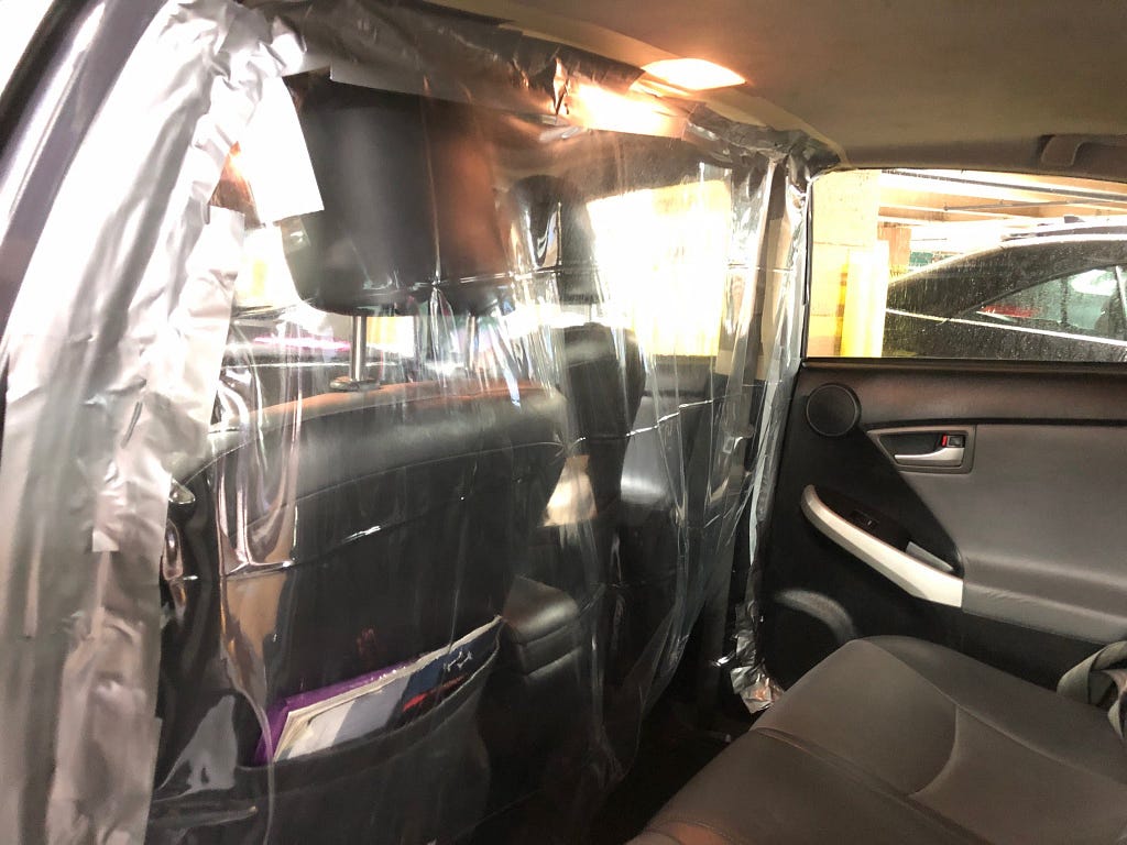 Image of the inside of a car. Plastic sheet dividing front and back passengers.