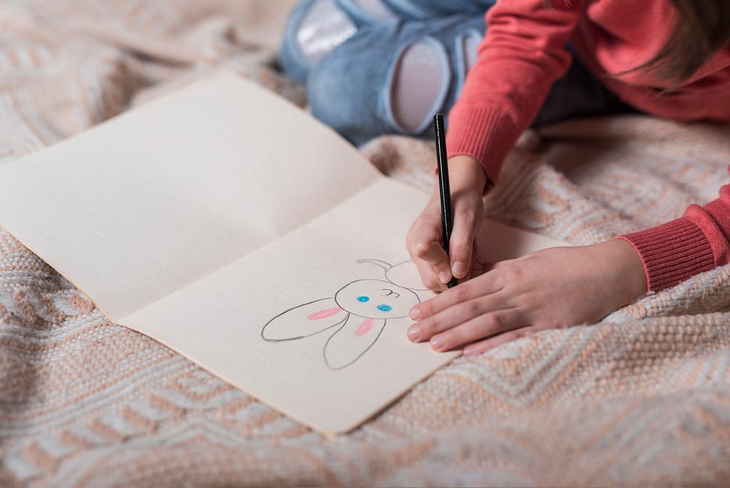 A kid drawing a rabbit on a bed