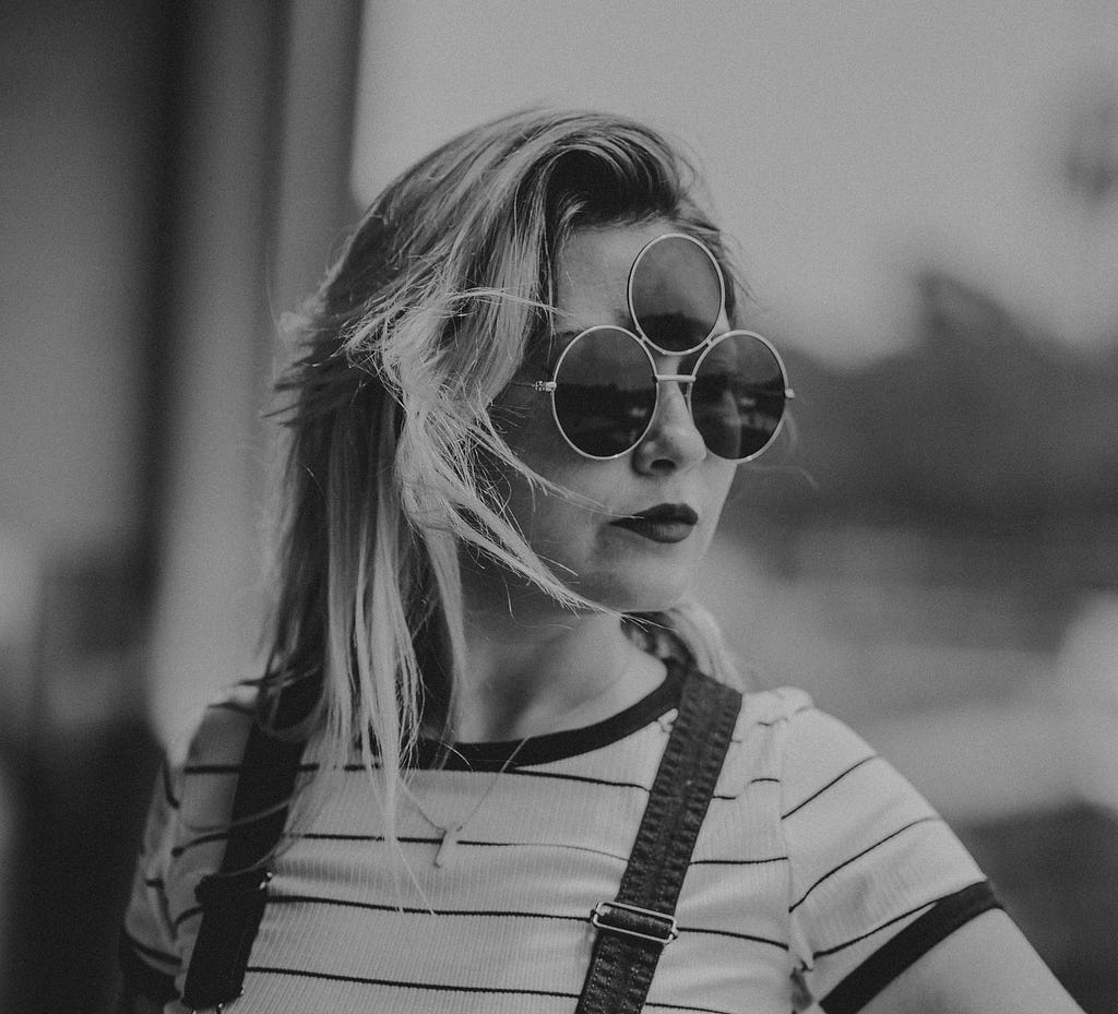 Grayscale photograph of a woman wearing sunglasses with three lenses, evoking the story title’s claim to weirdness.