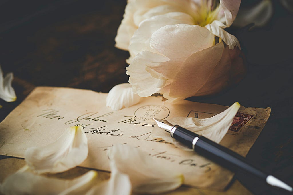 antique looking letter with calligraphy pen and white flower forgive